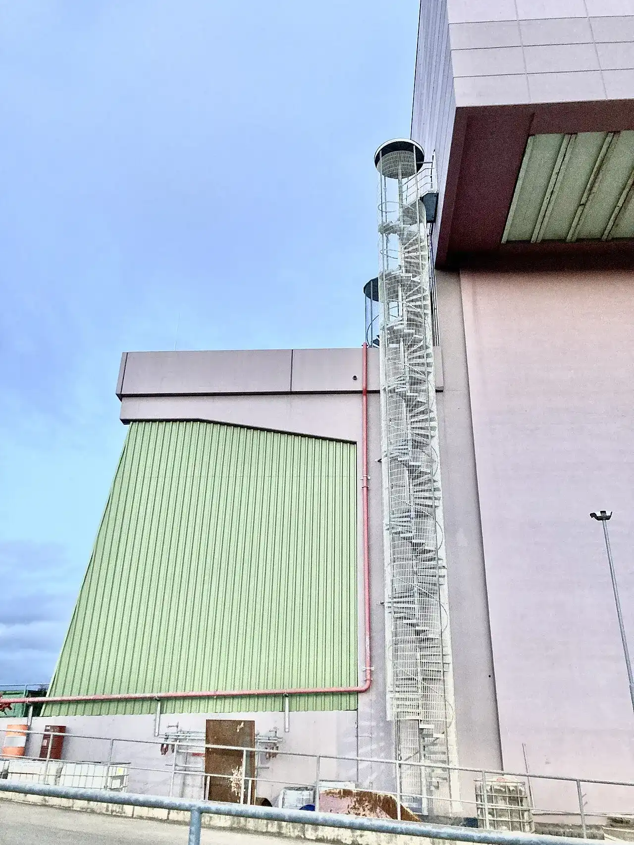Fassade der Müllverwertungsanlage Bonn in Endenich mit grünem Hallenteil und außenliegender Wendeltreppe